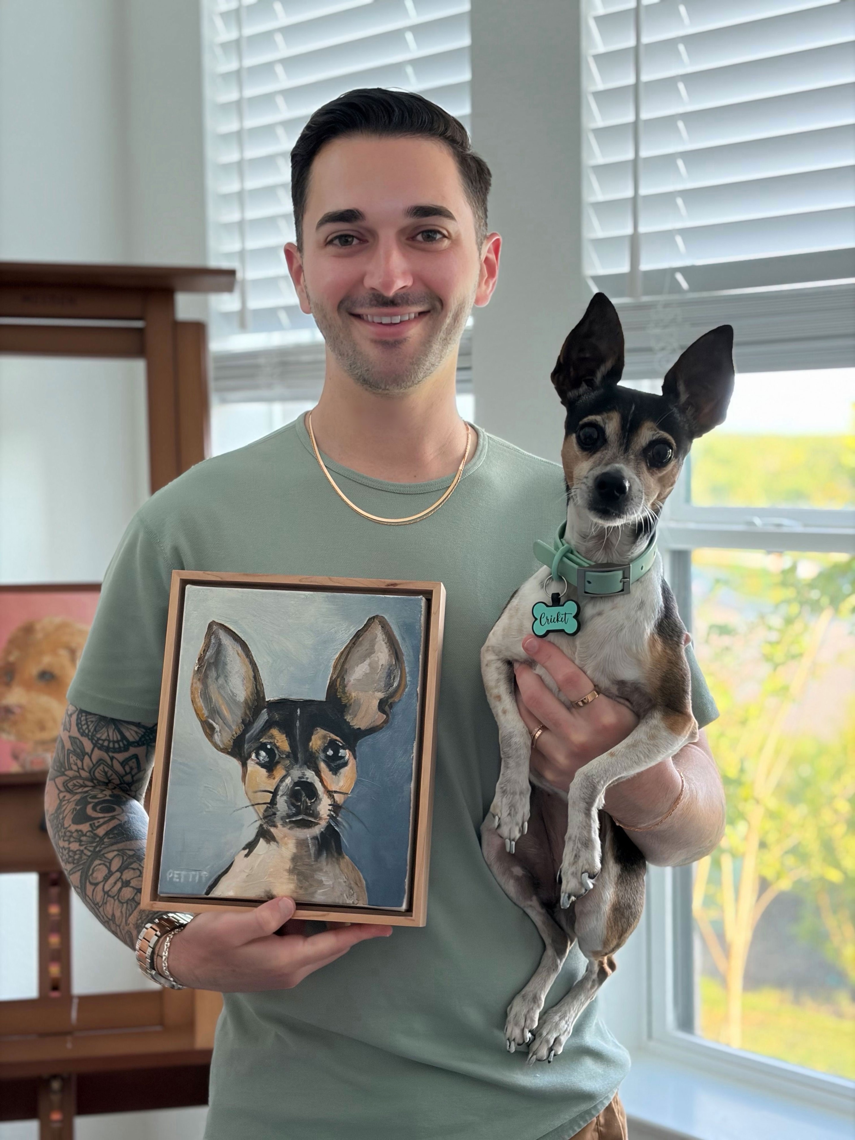 Matthew Pettit holding a pet portrait painting with his dog Cricket